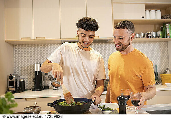 Gay male couple cooking in kitchen