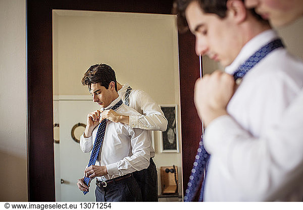Gay man assisting boyfriend for adjusting necktie