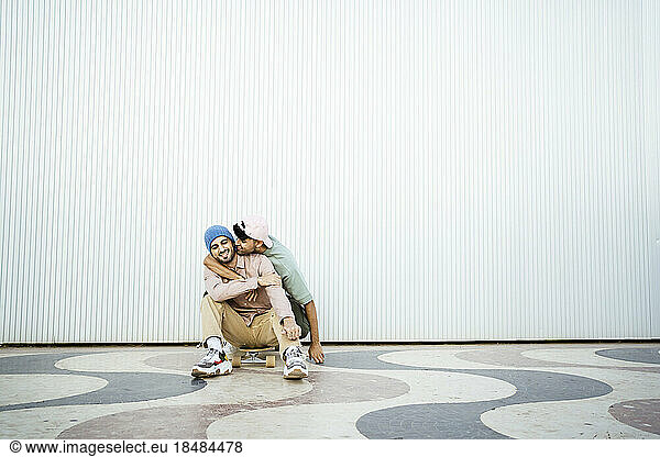 Gay man kissing boyfriend on footpath in front of white wall