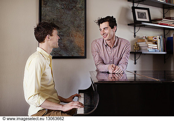 Gay man looking at boyfriend playing piano