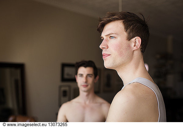 Gay men looking away while standing at home
