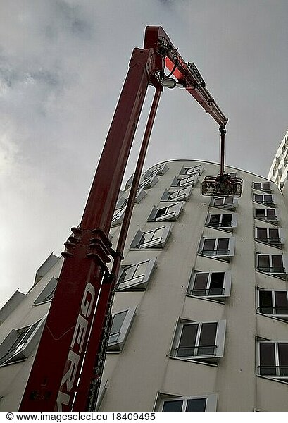 Gebäudereiniger auf einer Arbeitsbühne mit ausgefahrenem Kran am Gehry Bau Neue Zollhof 3  Düsseldorf  Nordrhein-Westfalen  Deutschland  Europa