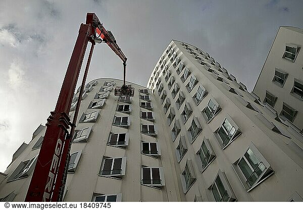 Gebäudereiniger auf einer Arbeitsbühne mit ausgefahrenem Kran am Gehry Bau Neue Zollhof 3  Düsseldorf  Nordrhein-Westfalen  Deutschland  Europa
