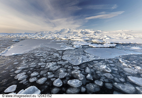 Gefrorene Jokulsarlon Gletscherlagune im Winter mit Eis im Vordergrund und schneebedeckten Bergen in der Ferne  Südisland  Polarregionen
