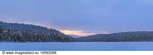 Gefrorener schneebedeckter See in der Winterlandschaft in Lappland bei Sonnenuntergang innerhalb des Polarkreises in Finnland