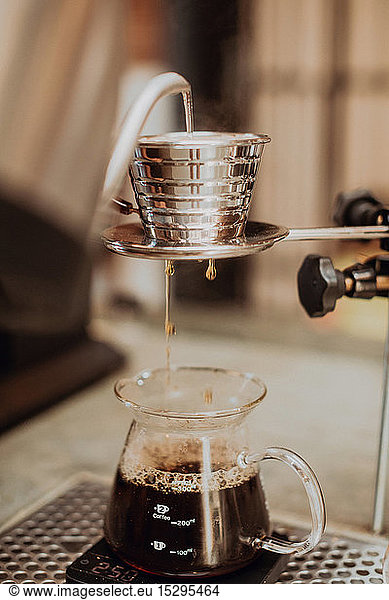 Gekochtes Kesselwasser  das in den Kaffeefilter läuft und in die Kanne auf der Kaffeetheke tropft  Nahaufnahme  flacher Fokus