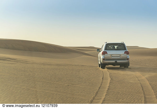 Geländefahrzeug fährt über Wüstendünen  Dubai  Vereinigte Arabische Emirate