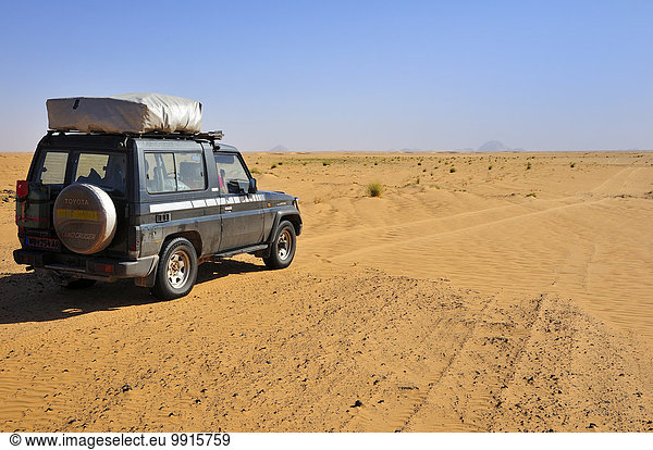 Geländefahrzeug mit Dachzelt auf der Piste  hinten der Monolith Aicha  Region Adrar  Mauretanien  Afrika