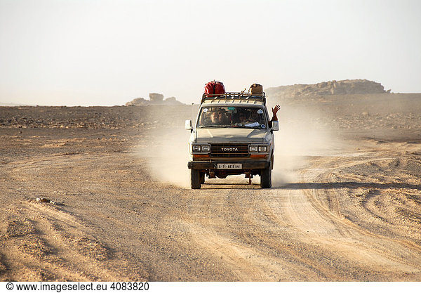 Geländewagen fährt auf staubiger Piste durch die Wüste Akakus Libyen