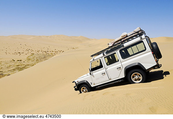 Geländewagen Landrover Defender fährt hohe Düne herunter Namib Naukluft Nationalpark Teil des Namib-Skelettküste Nationalparks Skeleton Coast Wüste Namib Namibia Afrika