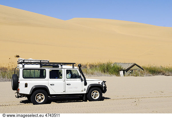 Geländewagen Landrover Defender und verlassenes Holzhaus im Feuchtgebiet Sandwich Harbour  Namib Naukluft Nationalpark  Teil des Namib-Skelettküste Nationalparks  Skeleton Coast  Wüste Namib  Namibia  Afrika