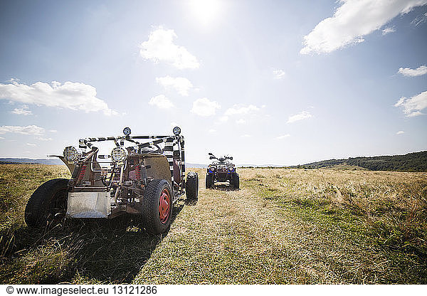 Geländewagen und Quadbike auf Grasfeld gegen den Himmel