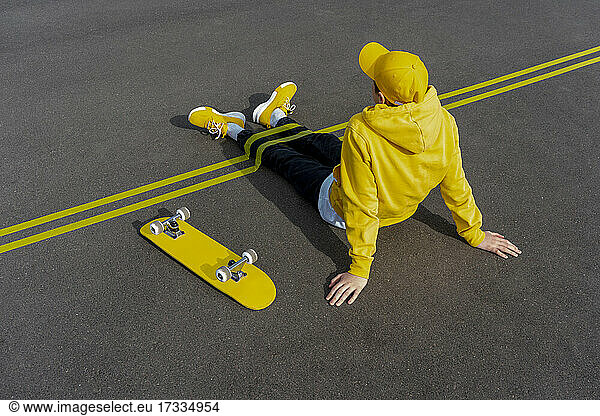 Gelbe Klebebänder über den Beinen eines Jungen mit einem Skateboard auf der Straße