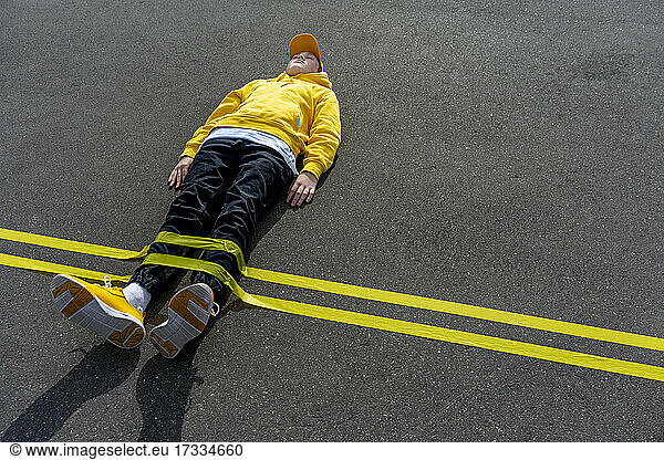 Gelbe Klebebandmarkierung über einem auf der Straße liegenden Jungen
