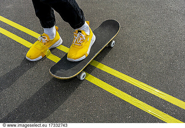Gelbes Klebeband am Schuh eines Jungen  der auf der Straße Skateboard fährt