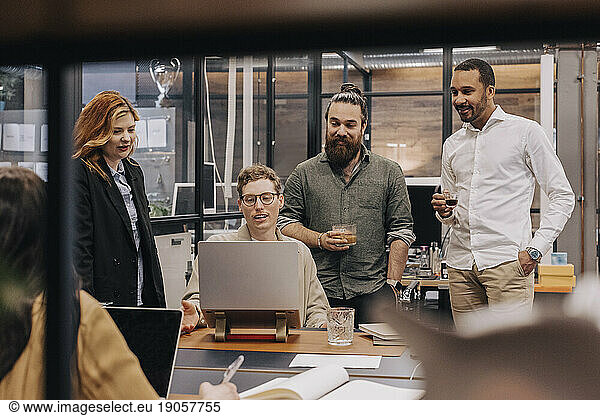 Gemischtrassige Geschäftskollegen  die über einen Laptop diskutieren  während sie im Büro eine Strategie planen