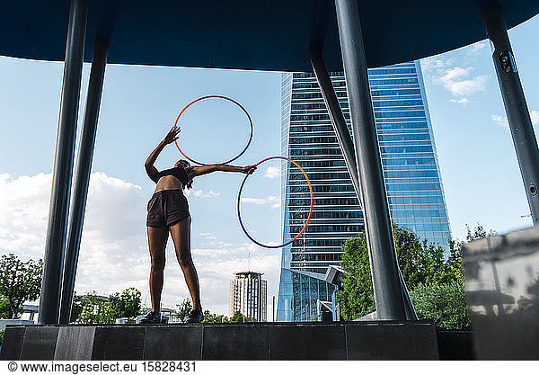 Generation Z woman performing Hula Hoop dance with rings in downtown