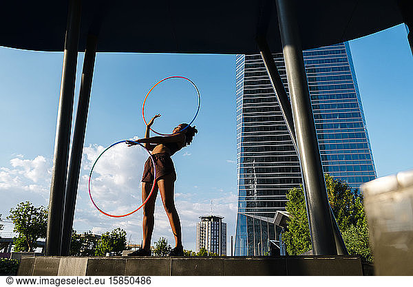 Generation Z woman performing Hula Hoop dance with rings in downtown