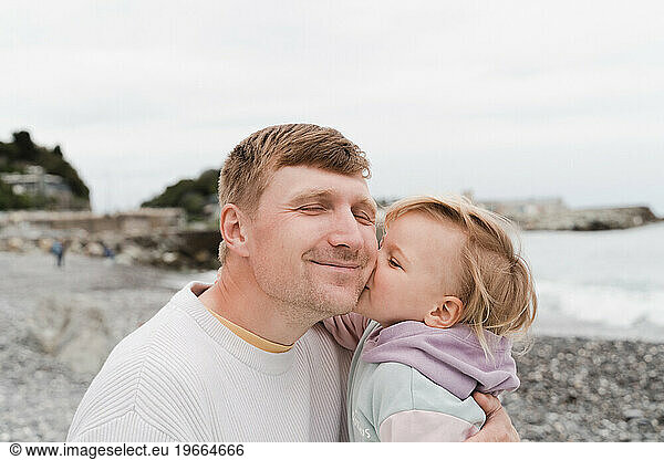 Gentle portrait of dad and baby daughter on the seashore in cold