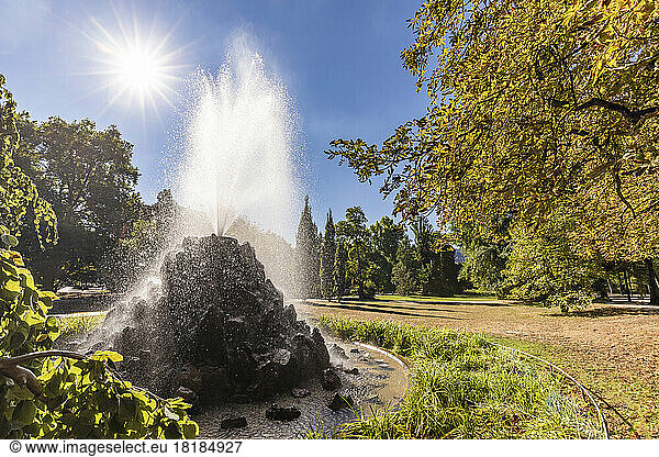 Germany  Baden-Wurttemberg  Baden-Baden  Sun shining over splashing fountain in Lichtentaler Allee park