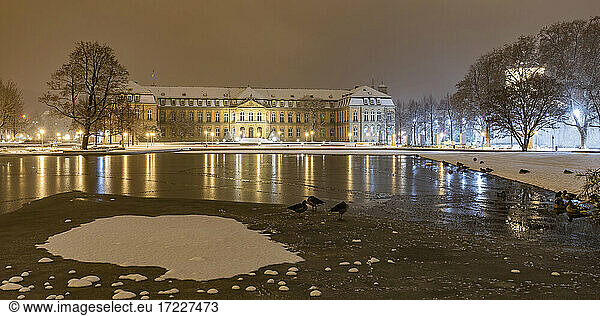 Germany  Baden-Wurttemberg  Stuttgart  Shore of Eckensee lake in Schlossgarten at winter night with New Palace in background
