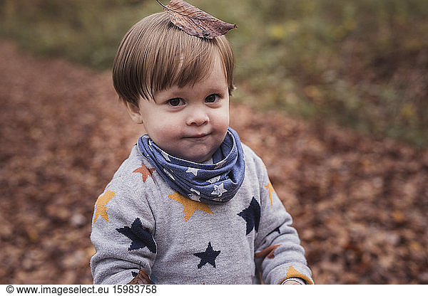 Germany  Baden-Wurttenberg  Lenningen  Portrait of little boy standing outdoors with fallen leaf on top of head