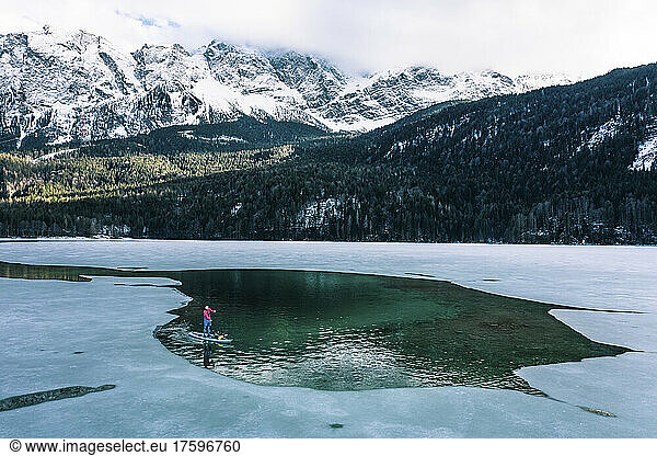 Germany  Bavaria  Aerial view of lone man paddleboarding between ice floes in Eibsee lake