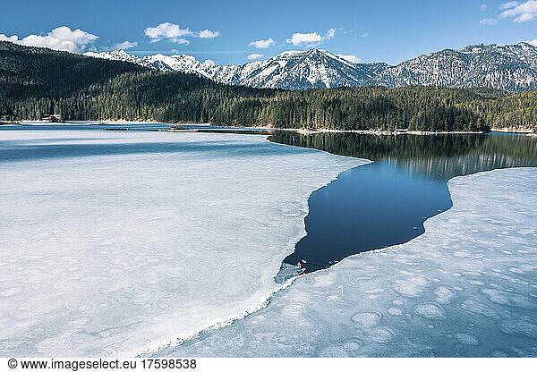 Germany  Bavaria  Aerial view of lone man paddleboarding between ice floes in Eibsee lake