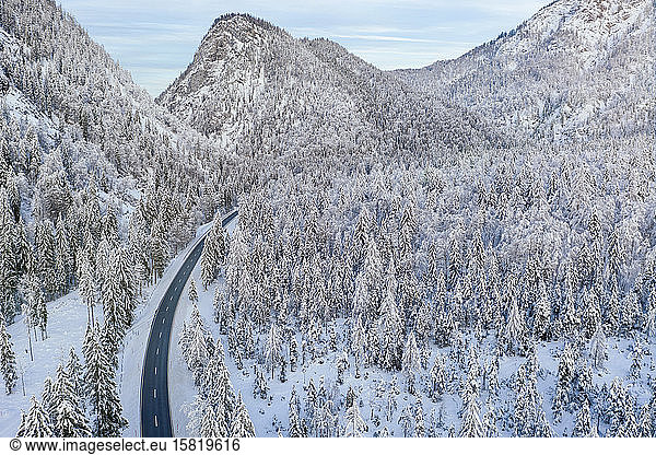 Germany  Bavaria  Aerial view of mountain highway and snow-covered forest in winter