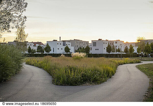 Germany  Bavaria  Augsburg  Forking footpath at sunset with suburban houses in background