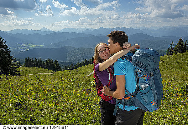 Germany  Bavaria  Brauneck near Lenggries  happy young couple hugging and kissing in alpine landscape