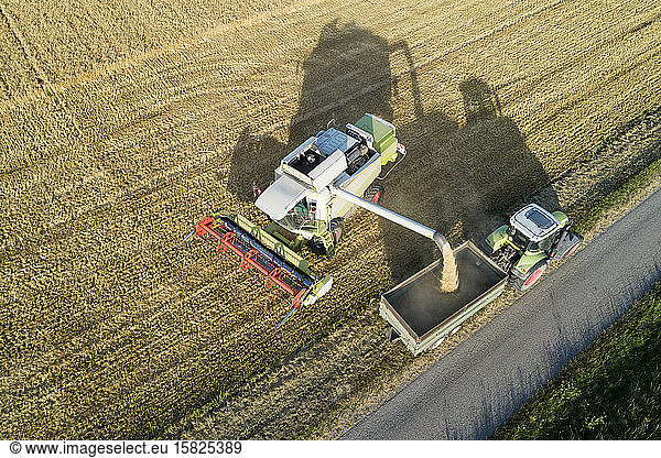 Germany  Bavaria  Drone view of combine harvester unloading grain on tractor