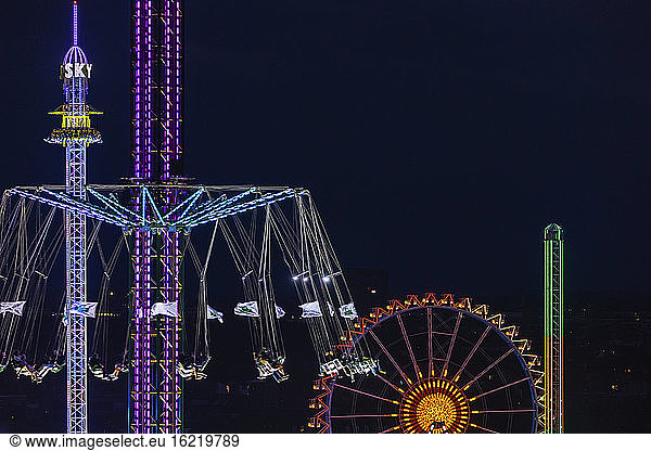 Germany  Bavaria  Munich  Aerial view of illuminated chain swing ride and Ferris wheel at night