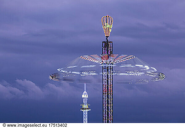 Germany  Bavaria  Munich  Aerial view of illuminated chain swing ride spinning against purple sky at dusk