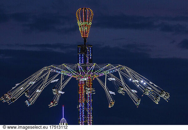 Germany  Bavaria  Munich  Aerial view of illuminated chain swing ride spinning against sky at night