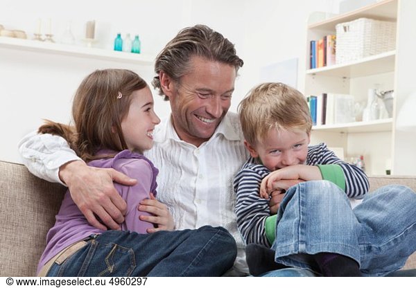 Germany  Bavaria  Munich  Father with kids on couch  laughing