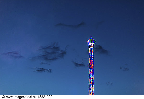 Germany  Bavaria  Munich  Low angle view of Bayern Tower chain swing ride glowing against sky at dusk