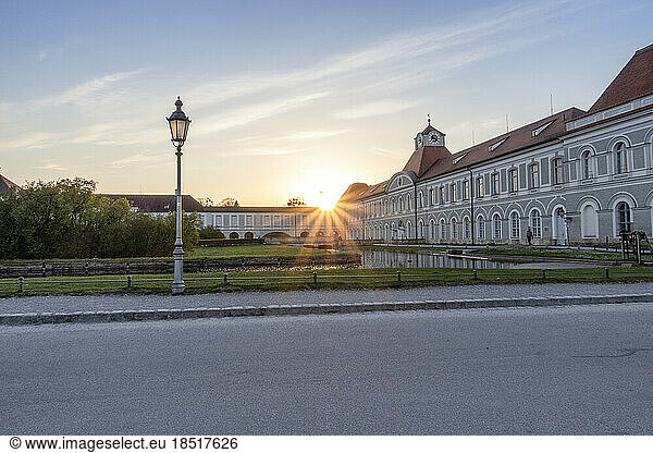Germany  Bavaria  Munich  Sun setting over Nymphenburg Palace with empty street in foreground