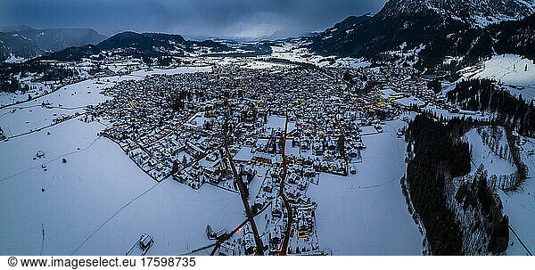 Germany  Bavaria  Oberstdorf  Helicopter panorama of snow covered town in Allgau Alps at dusk