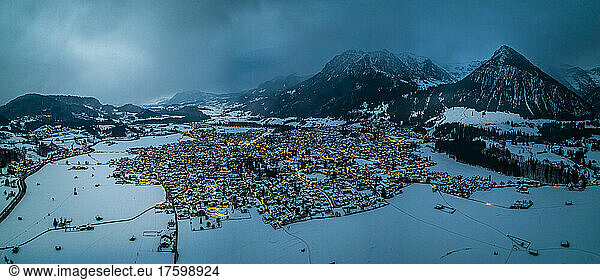 Germany  Bavaria  Oberstdorf  Helicopter panorama of snow covered town in Allgau Alps at dusk