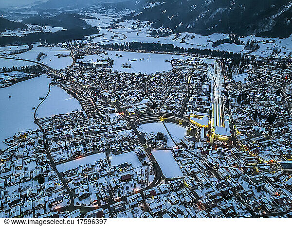 Germany  Bavaria  Oberstdorf  Helicopter view of snow covered town in Allgau Alps at dusk