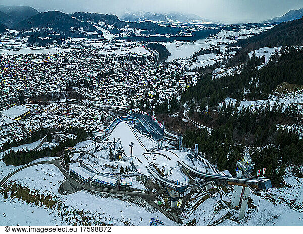 Germany  Bavaria  Oberstdorf  Helicopter view of snow covered town in Allgau Alps with ski jumping ramp in foreground