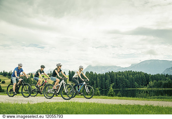 Germany  Bavaria  Pfronten  family riding mountain bikes at ladeside