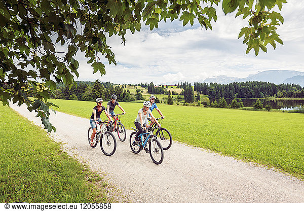 Germany  Bavaria  Pfronten  family riding mountain bikes at ladeside