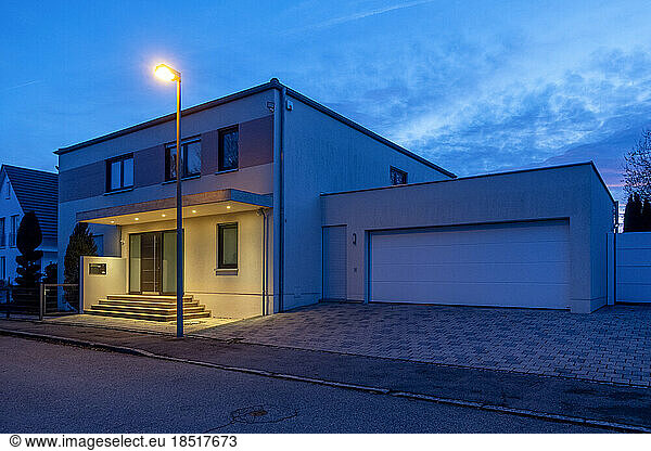 Germany  Bavaria  Street light glowing in front of modern suburban house at dusk