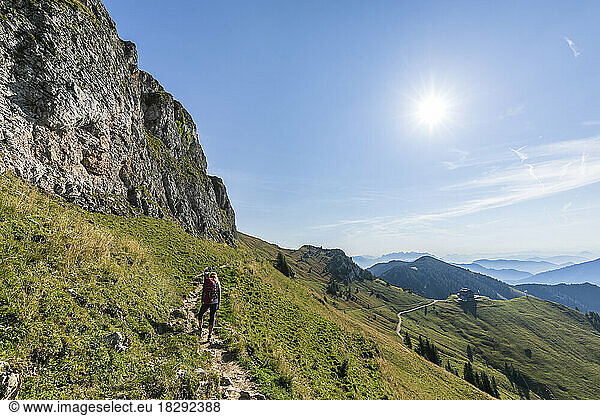 Germany  Bavaria  Sun shining over female hiker following trail to summit of Rotwand mountain