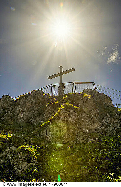 Germany  Bavaria  Sun shining over summit cross on Nebelhorn mountain