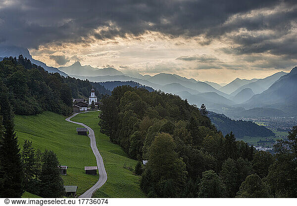 Germany  Bavaria  Wamberg  Clouds over small road leading to remote village in Wetterstein mountains