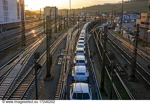 Germany  Bavaria  Wurzburg  Row od cars transported along city railroad tracks at sunset