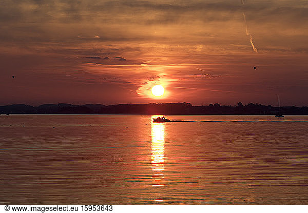 Germany  Bavria  Lake Chiemsee  Silhouette of lone motorboat sailing at moody sunset